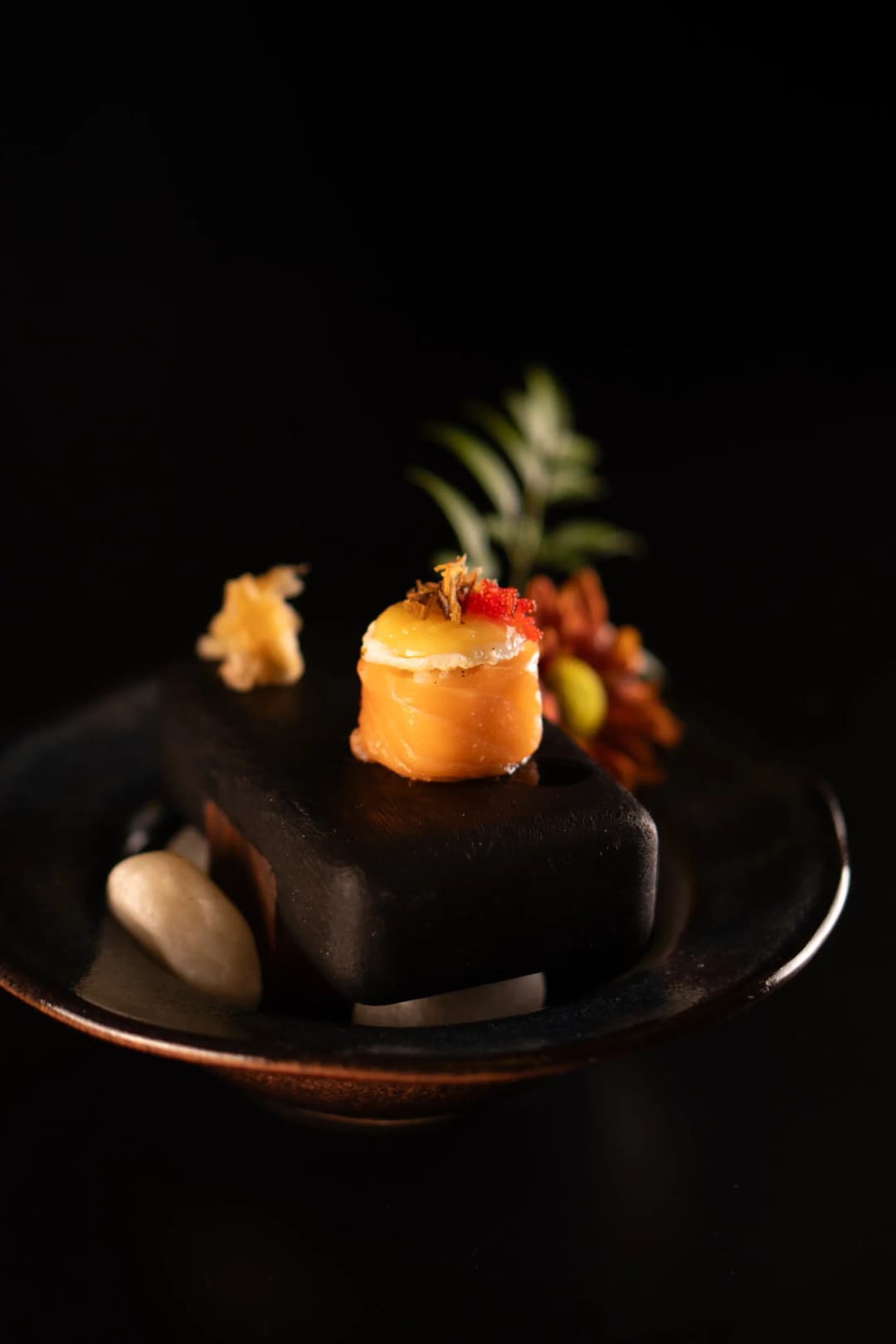 Quailzushi — Arroz envolto no Salmão Maçaricado, Ovo de Codorna, Azeite com Trufa, Couve Crocante, Milho Espanhol, Pimenta Srirasha, Flor de Sal