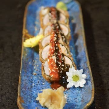 Eskulasho Roll — Salmão, Peixe Branco, Caranguejo envoltos na alga marinha empanado no Panko condimentado com geleia de pimenta e geleia de alho negro.